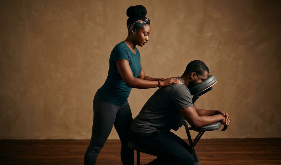 A therapist giving a chair massage to a client leaning on a massage chair
